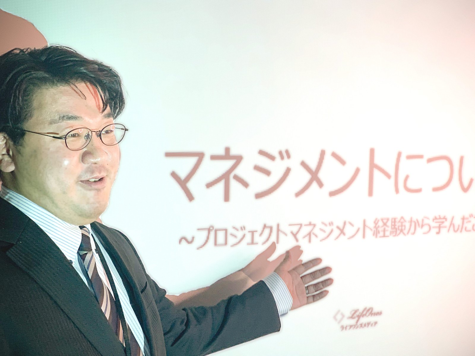 スライドを指して話す代表 徳本
